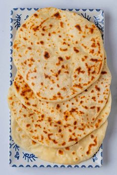 three flat breads on a blue and white plate