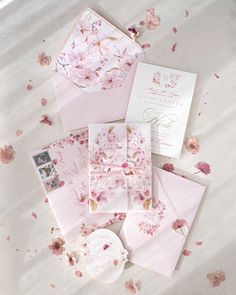 the wedding stationery is laid out on top of the bed with pink flowers all over it