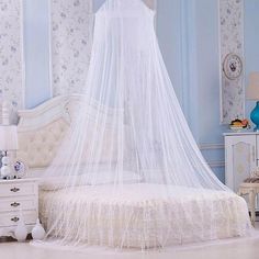 a bed with a white canopy in a blue and white room, surrounded by floral wallpaper