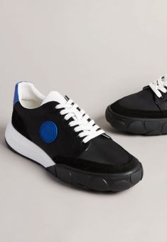 black and white sneakers with blue accents on the soles, side by side against a gray background