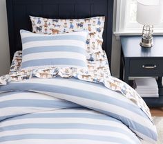 a bed with blue and white striped comforter next to a night stand in a bedroom