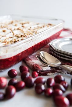 cranberry dessert in a glass dish with spoons and plates on the side