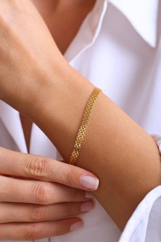 a woman wearing a gold bracelet and white shirt