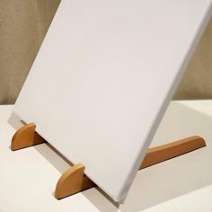 an easel with wooden handles on top of a white table cloth covered chair cushion