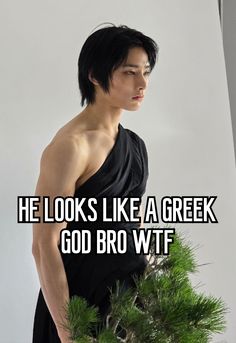 a man in a black dress holding a green plant with the caption he looks like a greek god bron wt