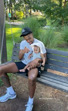 a man sitting on a swing holding a baby