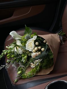 a bouquet of flowers sitting on top of a brown leather seat in the back of a car