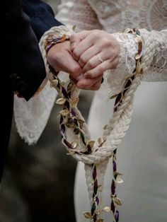 a close up of a person holding the hands of another person wearing a wedding dress