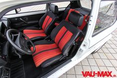 the interior of a white car with red and black striped seats on it's side