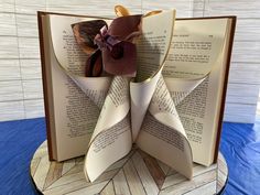 an open book with folded pages and a flower on the top, sitting on a table