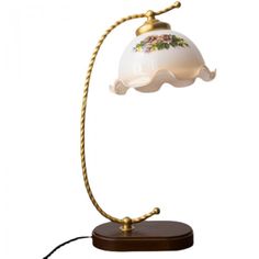 a lamp that is on top of a wooden base with a white shade and flowers painted on it