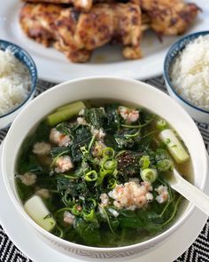 a white bowl filled with soup next to rice and chicken