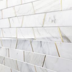 a white marble tile wall with gold lines