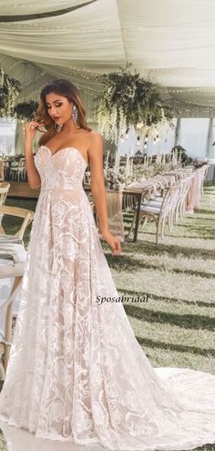 a woman standing in front of a white tent wearing a wedding dress with an open back