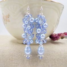 This pair of special earrings was artfully designed and hand crafted by ME in my Wisconsin USA studio.  If you want a unique pair of statement earrings you have come to the right place!  This pair of Light Blue earrings is made with genuine top quality name brand Elements brand crystals and pearls in Light blue and Light Sapphire Blue.  The pearls are round and pear shaped, and the crystals are done in the bicone shape.  Each pearl and crystal has been hand wired into place by me.  The earrings Adjustable Blue Pearl Drop Jewelry, Handmade Blue Dangle Pearl Earrings, Blue Dangle Chandelier Earrings For Anniversary, Blue Dangle Bridal Earrings With Pearl Drop, Blue Pearl Drop Bridal Earrings As Gift, Blue Drop Cluster Earrings For Gift, Blue Cluster Drop Earrings As Gift, Blue Dangle Earrings For Bridesmaids, Light Blue Beaded Dangle Earrings For Party