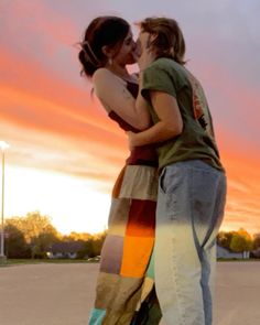 two people standing next to each other with their arms around each other and one person kissing the other