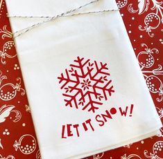 a red and white table cloth with a snowflake on it that says let it snow