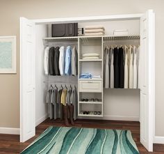 an open closet with clothes on hangers and rug in the floor next to it