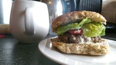 a close up of a sandwich on a plate with a cup in the back ground