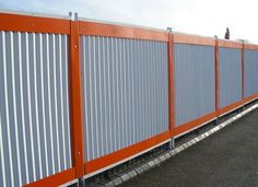 an orange and white fence next to a road