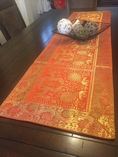 an orange and gold table runner on top of a wooden table