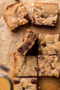 chocolate chip cookie bars cut into squares and placed on parchment paper with peanut butter in the background