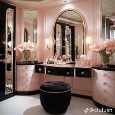 a pink and black vanity with flowers in vases on the top shelf next to it