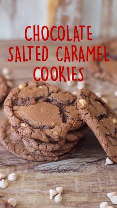 two chocolate cookies are on a wooden table with white nuts scattered around them and one cookie has been cut in half