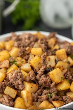 a white bowl filled with meat and potatoes