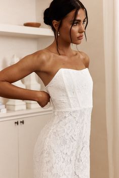 a woman in a white dress is posing for the camera with her hands on her hips