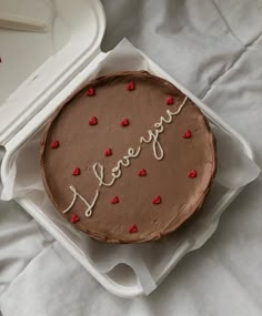 a chocolate cake with the word love spelled in frosting and hearts around it on a white tray