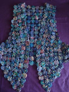 two pieces of blue and green glass beaded fabric on a purple cloth covered tablecloth