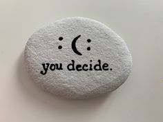 a rock with the words you decide written on it and a smiley face drawn on it