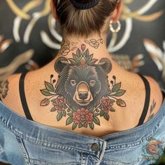 a woman with a bear tattoo on her upper back neck and behind her is a denim jacket