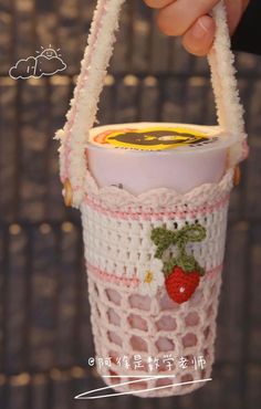 a hand holding a small cup holder with strawberries on the side and a strawberry in it