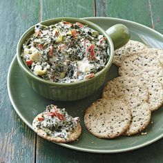 a green plate topped with crackers and a bowl of dip