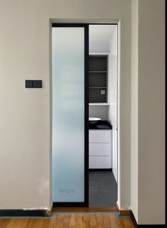 an open door leading to a kitchen with white cabinets and black trim on the walls