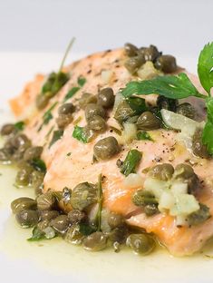 a white plate topped with salmon covered in green beans and garnished with parsley