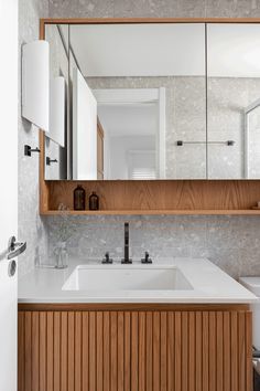 a white sink sitting under a large mirror next to a wooden cabinet and counter top