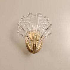 a glass scallop is mounted on the wall by a gold plated handle