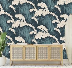 a wallpapered room with an ocean wave design on the wall and a wooden cabinet next to it