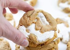 a close up of a person holding a cookie with marshmallows