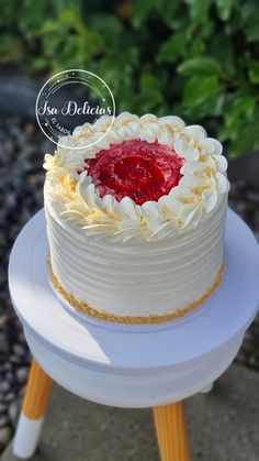 a white cake sitting on top of a table next to a green leafy bush