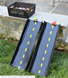 two wooden road signs sitting on top of a grass covered field next to a black box