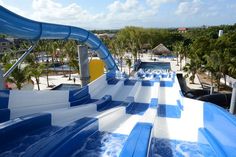 an inflatable water slide with blue and white stripes on the side, next to palm trees