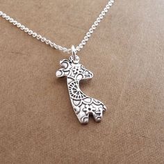 My Tiny Giraffe Necklace is handmade using fine silver and my original giraffe design.  Her pretty flowered pattern is highlighted by oxidizing and then buffing her to a soft, brushed finish. The back is stamped with my dragonfly maker's mark and ".999" to signify fine silver. Your choice of sterling silver chain is included.S I Z E : About 1" tall (25 mm) including the ring.A V A I L A B I L I T Y :  Made-to-order, ships 1-2 weeks after purchase unless otherwise noted above.Because I make each Handmade Whimsical Silver Necklaces, Whimsical Handmade Silver Necklaces, Giraffe Jewelry, Giraffe Design, Giraffe Necklace, Giraffes, Pretty Gift, Maker's Mark, Silver Flowers