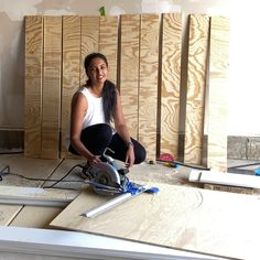 a woman is sitting on the floor in front of some plywood planks with a circular saw