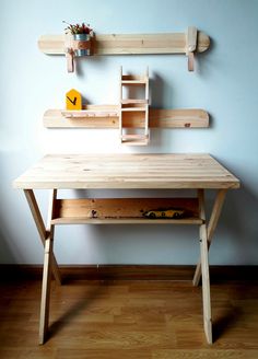 a wooden desk sitting on top of a hard wood floor next to a white wall