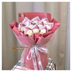 a bouquet of white roses wrapped in pink paper