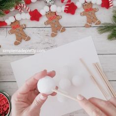 someone is making some christmas decorations with cotton balls and wooden chopsticks on the table